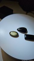 Three Gold Sheen Obsidian cabochons on white background showing their polished surfaces and golden shimmer.