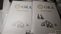 GRA Moissanite Report certification booklet covers alongside the pair of stud earrings