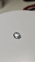 Close-up photo of the oval cut natural aquamarine gemstone showing its light blue color and clarity.