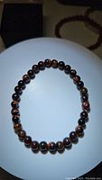 Front view of the natural red tigerseye bracelet showing polished round beads with chatoyancy and red-brown colors.