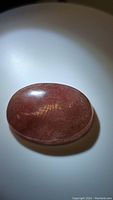 Oval cabochon natural strawberry quartz gemstone with smooth polished surface and reddish-pink color.
