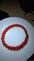 Top view of orange carnelian beaded stretchy bracelet illuminated by direct light showing bead color and polish.