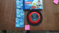 Vileda Virobi floor cleaner device with attached packages of dust refills on a wooden surface.