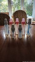 Eight Dr. Brown's baby bottles: four pink bottles with caps and nipples, four clear bottles with white caps and internal vent systems without nipples.