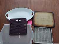 Photo showing all five kitchen items including two platters, baking stone, baking tray with wire rack, and silicone pastry cutter on wooden table