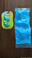 Photo showing one package of two unopened green First Sounds pacifiers and three separate unopened blue Hamilton GumDrop Full-Term Unscented pacifier packages.