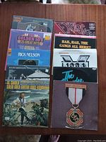 Photo showing 10 assorted vinyl record albums stacked, titles and artists visible on some covers.