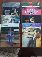 Top view of 10 country vinyl record albums arranged in two columns, showing album covers by Lee Greenwood, Lefty Frizzell, George Jones, Conway Twitty and others.