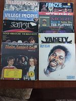 Photo of all 10 record albums stacked, showing front covers with artist names and titles for identification.