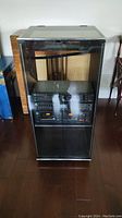 Front view of stereo cabinet showing glass doors with stereo components visible inside.