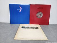 Three King Crimson vinyl record albums arranged to show front covers: blue with musical note, red with Celtic knot, and white with album text.