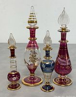 Four vintage Egyptian hand blown perfume bottles grouped together showing full view and details of colors and gold decoration.