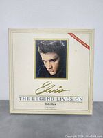 Front album cover with Elvis Presley's color photo, gold signature, and 'The Legend Lives On' title