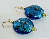 Close-up image of the blue and green Murano glass earrings showing gold hooks and chain detail.