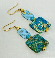 Pair of Murano glass earrings with square turquoise stones and gold-tone spacer beads displayed on white background.