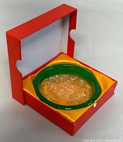 Natural green jade bangle in original red box with yellow satin lining.