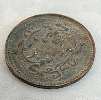 Close up photo of the coin lying flat on a light surface showing the dragon design engraved.