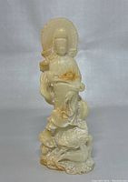 Front view of the white jade Kwan-yin statue showing detailed carving of the goddess and mythical creature beneath her.