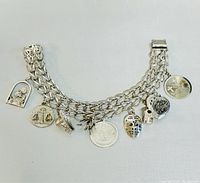 Full view of sterling silver charm bracelet laid flat showing all charms.