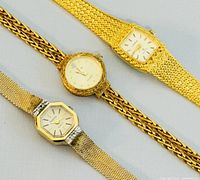 Front top view of three vintage ladies wrist watches showing dial shapes and gold-tone bands.