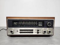 Front view showing tuning dial, input selector knob, tone sliders, signal meters and volume control