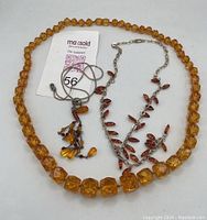 Photo showing the three amber necklaces side by side, exhibiting their different bead size, color, and chain styles.