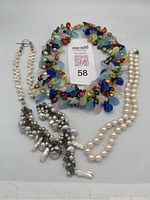 Photo of three necklaces: one white freshwater pearl necklace, one mixed pearl cluster necklace, and one colorful multicolored glass bead necklace.