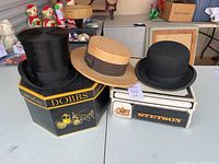 Three hats displayed: beaver fur top hat on Dobbs Fifth Avenue box, straw boater, Stetson bowler on Stetson box