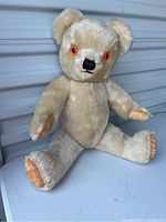 Full body image of the light beige mohair teddy bear seated, showing jointed arms and legs and felt pads on hands and feet with minor wear.