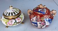 Photo showing both porcelain pots side by side on a white surface, depicting shapes and colors.