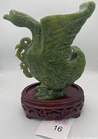 Front and side view of the carved jade phoenix figure on the wooden stand showing full profile and wing details.