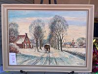 Framed oil on canvas painting of a Dutch winter scene with horse-drawn carriage and village