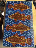 Full view of the canvas painting showing four stylized fish on a detailed swirling pattern background. The colors include blue, brown, red, yellow, and white.