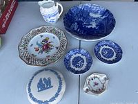 Top-down view of all seven china pieces arranged on a table showing variety of plates, bowl, and pitcher.