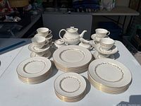 Overview of full set arranged on table showing plates, cups, saucers, teapot, sugar and creamer.