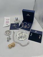 Overview of all nine items on white surface, showing figurines, bracelets, brooch, earrings, necklace, box and certificate