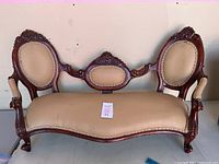 Front view of miniature Victorian style settee showing three upholstered padded panels and wood frame with carved details.