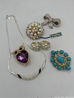Overview photo showing all six pieces including necklace, owl brooch, cluster earrings, turquoise brooch, and ribbon brooch with Vendome tag visible