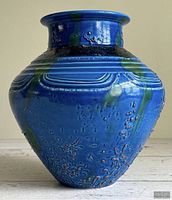 Front view of blue glazed vase showing applied texture and green drip accents