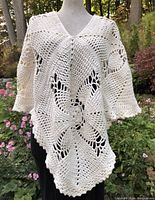 Full front view of crocheted cream white poncho on mannequin