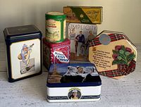 Seven vintage tins grouped together showing a variety of shapes, colors and designs including a tall rectangular tin with a man, square Philips Crisp Crunch tin, cylindrical Pennsylvania Dutch Toffees tin, Simplicity fashion tin, hexagonal plaid floral tin with sentimental text, and others.