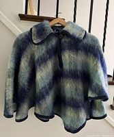 Front view of the vintage Fraser Cameron mohair wool cape showing dark teal and purple striped fuzzy fabric, large collar, and black trim edges.