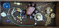 Full view of drawer containing various costume jewellery items including pins, bracelets, necklaces, and pendants.