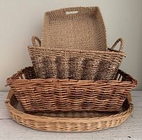 Four nested wicker and sea grass baskets and trays showing the set and materials