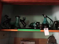 Shelf view of Blue Mountain Pottery items including pitchers, animal figurines, and a vase in green and brown glaze.