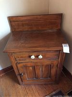 Full view of the vintage wooden wash stand cabinet showing the top, drawer, cupboard door, and overall structure.