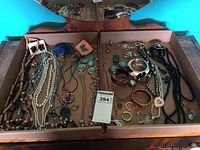 Wide shot of costume jewelry pieces displayed in two cardboard trays including necklaces, bracelets, earrings and brooches.