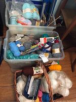 Overview of bins and baskets containing numerous yarn skeins, knitting needles, and crochet supplies