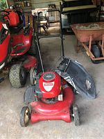 Front view of the red Craftsman push lawn mower showing the cutting deck, wheels, handlebar, and attached grass collection bag.