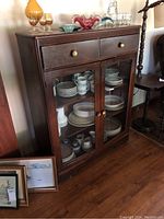 Full view of wooden sideboard cabinet with contents inside showing dishes and glassware, illustrating size and style.